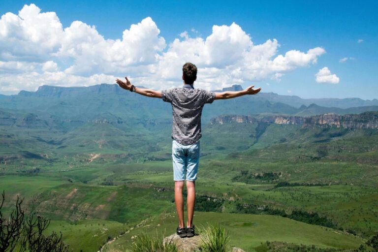 Man stood on a hilltop looking outwards with arms stretched. Showing the self-improvement and development Freemasonry promotes.