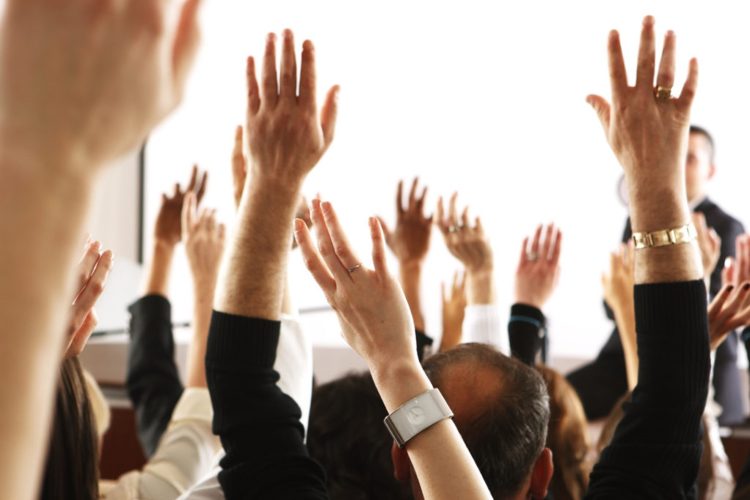 Group of hands raised asking questions